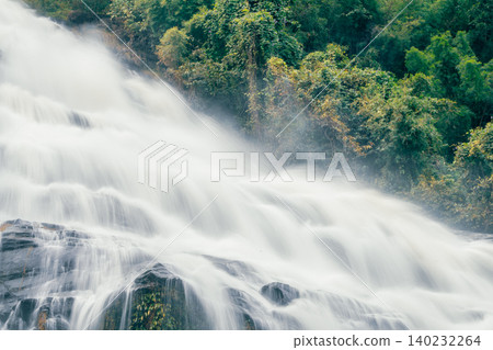 Beautiful waterfall with a lush green forest in the background. The water is flowing down the rocks and creating a beautiful scene. Sustainable waterfall in lush forest promoting water sustainability. Beautiful waterfall with a lush green forest in the background. The water is flowing down the rocks and creating a beautiful scene. Sustainable waterfall in lush forest promoting water sustainability. 140232264