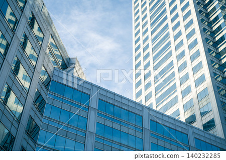 Skyscraper glass building of corporate headquarters in the downtown business area. Towering facade and windows embodying sleek, modern office environment. Financial institution. Modern architecture. Skyscraper glass building of corporate headquarters in the downtown business area. Towering facade and windows embodying sleek, modern office environment. Financial institution. Modern architecture. 140232285