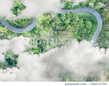 Aerial top view of electric vehicle driving on a winding highway road in green forest with fog. Sustainable transportation, zero emissions, and eco-friendly mobility for reducing carbon footprints. Aerial top view of electric vehicle driving on a winding highway road in green forest with fog. Sustainable transportation, zero emissions, and eco-friendly mobility for reducing carbon footprints. 140232339