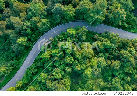 Aerial view of dense green trees in forest capture CO2 and curve highway road. Green trees background for carbon neutrality and net zero emissions concept. Sustainable green environment. Carbon credit Aerial view of dense green trees in forest capture CO2 and curve highway road. Green trees background for carbon neutrality and net zero emissions concept. Sustainable green environment. Carbon credit 140232343