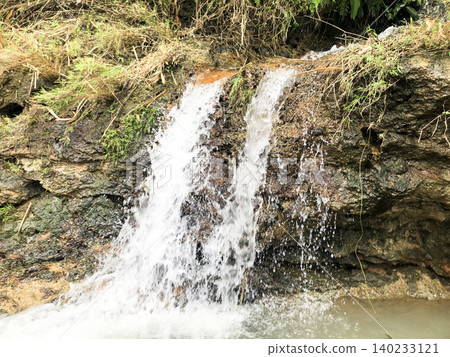 Small Waterfall Flowing Over Rocky Cliff Small Waterfall Flowing Over Rocky Cliff 140233121