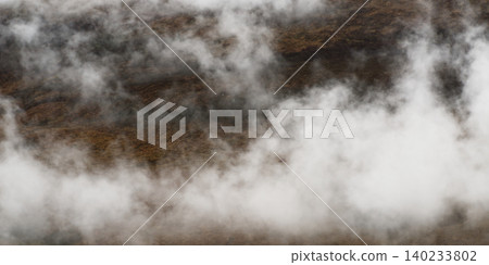 Dense white fog blankets a rugged mountainous landscape, obscuring distant peaks and valleys in a natural scene. Dense white fog blankets a rugged mountainous landscape, obscuring distant peaks and valleys in a natural scene. 140233802