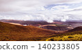 A scenic view of a mountainous region with green woods and patches of light. 140233805
