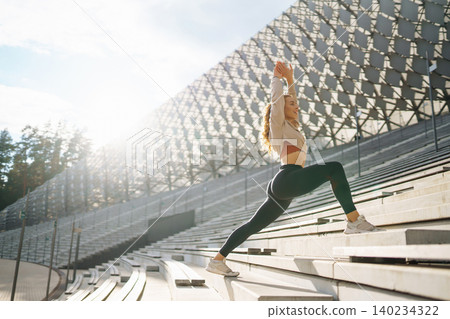 Active woman in sportswear does stretching exercise, looks at fitness application through Smartwatch Active woman in sportswear does stretching exercise, looks at fitness application through Smartwatch 140234322