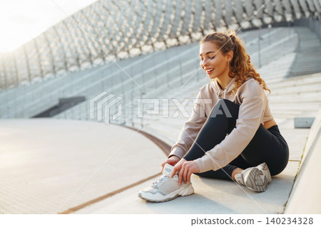 Active woman in sportswear does stretching exercise, looks at fitness application through Smartwatch Active woman in sportswear does stretching exercise, looks at fitness application through Smartwatch 140234328
