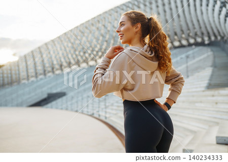 Active woman in sportswear does stretching exercise, looks at fitness application through Smartwatch Active woman in sportswear does stretching exercise, looks at fitness application through Smartwatch 140234333
