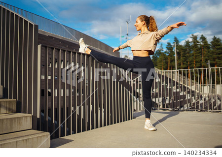 Active woman in sportswear does stretching exercise, looks at fitness application through Smartwatch Active woman in sportswear does stretching exercise, looks at fitness application through Smartwatch 140234334