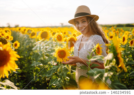Woman poses in sunflower field in a dress and hat. Enjoy the moment. Active lifestyle. 140234591