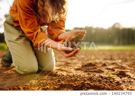 Farmer's woman's hands touch the soil in the field. Concept of gardening, agriculture. 140234793