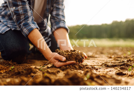Farmer's hands take the soil from field and check its quality. Experienced male hands hold the soil. Farmer's hands take the soil from field and check its quality. Experienced male hands hold the soil. 140234817