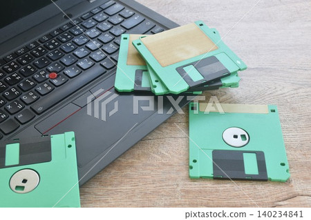 floppy disk old technology for saving data arranging with laptop computer on table 140234841