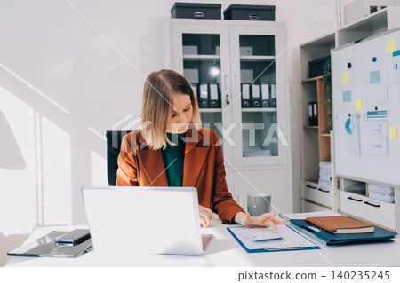 Woman smiling to herself as she works in an office 140235245