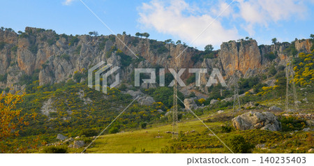 Scenic view of steep rocky mountains and green hills under a blue sky in Turkey Scenic view of steep rocky mountains and green hills under a blue sky in Turkey 140235403