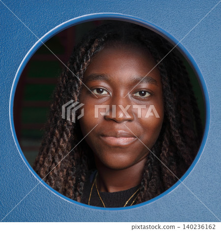 Smiling young Black woman framed by a blue circular cutout 140236162