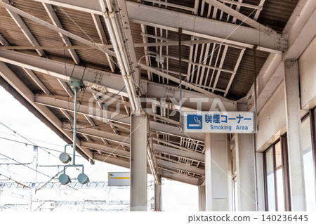 Sign for the smoking area on the Shinkansen platform and the steel roof of the station. Sign for the smoking area on the Shinkansen platform and the steel roof of the station. 140236445