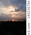 A fantastical sunset over the sea and horizon, with light streaming in from between the clouds. 140236784