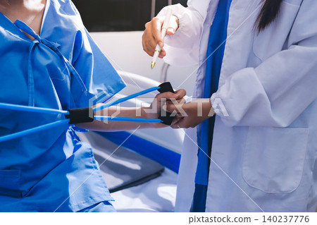 Physical therapist giving stretching exercises with elastic exercise bands and physical therapist hands helping male patient Physical therapy concept Physical therapist giving stretching exercises with elastic exercise bands and physical therapist hands helping male patient Physical therapy concept 140237776