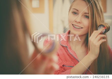 Woman curling her hair using rollers Woman curling her hair using rollers 140238135