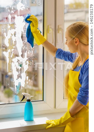 Woman cleaning window at home Woman cleaning window at home 140238179
