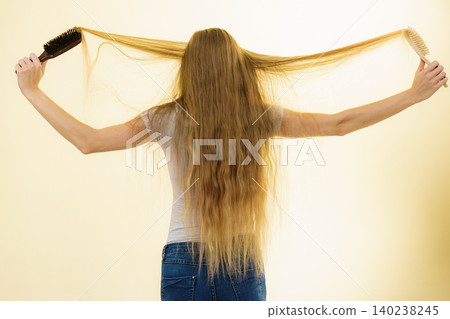 Blonde girl brushing her long hair Blonde girl brushing her long hair 140238245