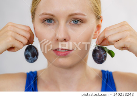 Girl holds plum fruit to her ear Girl holds plum fruit to her ear 140238248