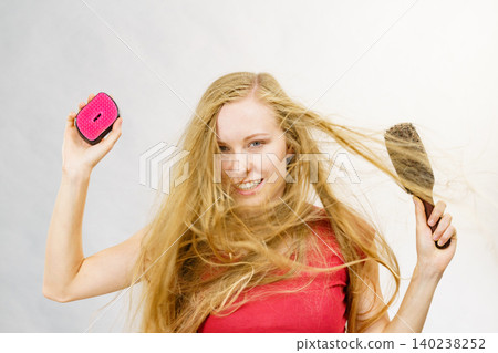 Blonde girl long blowing hair holds two brushes Blonde girl long blowing hair holds two brushes 140238252