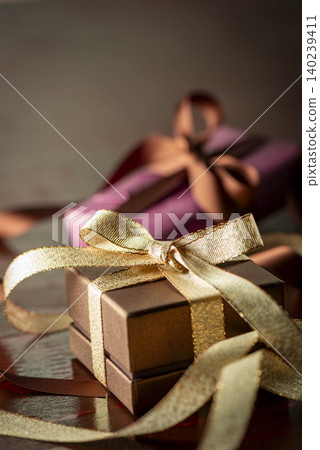 A gift tied with a gold ribbon adds a special touch to the moment of presenting a gift to a loved one. A gift tied with a gold ribbon adds a special touch to the moment of presenting a gift to a loved one. 140239411