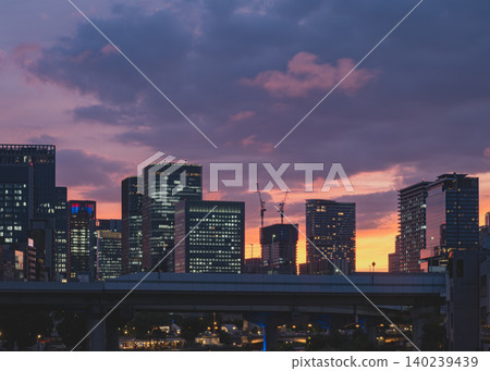 城市天際線和摩天大樓的輪廓沐浴在絢麗的夕陽餘暉中。 城市天際線和摩天大樓的輪廓沐浴在絢麗的夕陽餘暉中。 140239439