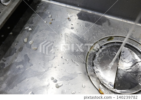 Dirt on the kitchen sink. A stainless steel sink covered in water droplets and food scraps. Dirt on the kitchen sink. A stainless steel sink covered in water droplets and food scraps. 140239782
