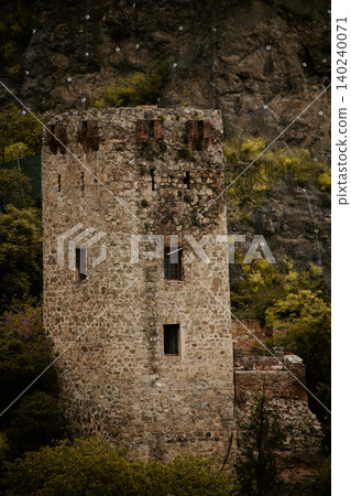Ancient Stone Watchtower Surrounded by Forest and Rocky Cliff, Medieval Fortress Ruins in Mountain Ancient Stone Watchtower Surrounded by Forest and Rocky Cliff, Medieval Fortress Ruins in Mountain 140240071