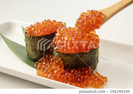 一桌上擺放著新鮮的壽司食材，鮭魚籽軍艦捲盛放在木匙上。 140240240