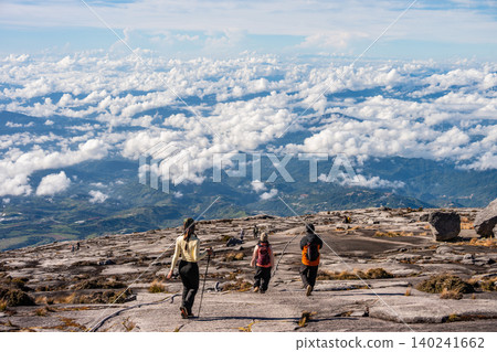 Rear view of tourist while walking on rock plateau on Mt.Kinabalu, Malaysia. Mt.Kinabalu is the highest mountain in Borneo and Malaysia. Rear view of tourist while walking on rock plateau on Mt.Kinabalu, Malaysia. Mt.Kinabalu is the highest mountain in Borneo and Malaysia. 140241662