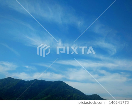 A landscape of cirrus clouds drifting across a blue sky and mountain ranges. A landscape of cirrus clouds drifting across a blue sky and mountain ranges. 140241773