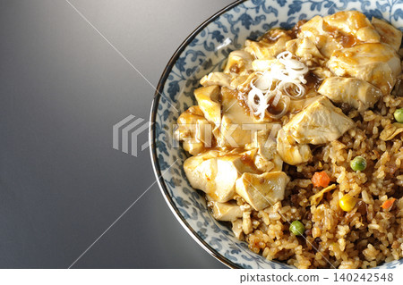 Mapo tofu-topped fried rice photographed against a black background. 140242548