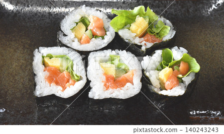 Homemade roll sushi on black plate on table. Homemade roll sushi on black plate on table. 140243243