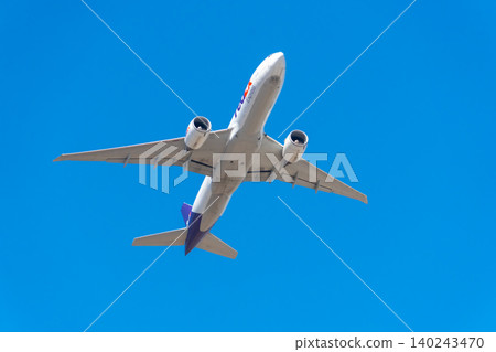 Image of a cargo plane flying through a blue sky - FedEx Image of a cargo plane flying through a blue sky - FedEx 140243470