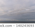 A beautiful ocean view with soft pink and gray clouds and the warm afterglow on the horizon. 140243693