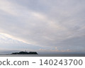 A sky filled with soft pastel pink clouds and the tranquil seascape of Enoshima Island. 140243700