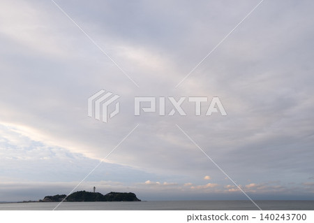 A sky filled with soft pastel pink clouds and the tranquil seascape of Enoshima Island. A sky filled with soft pastel pink clouds and the tranquil seascape of Enoshima Island. 140243700