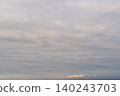 A calm, cloudy sky with a warm glow and lingering morning light. 140243703