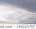 Gray clouds reflecting the morning sun and a clear blue sky stretching out above. 140243707