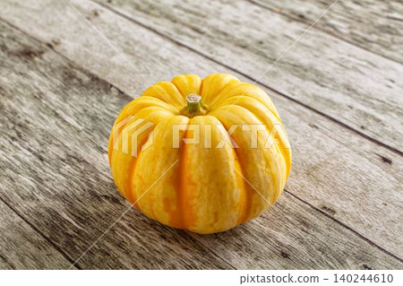 Small yellow pumpkin on rustic wooden table Small yellow pumpkin on rustic wooden table 140244610