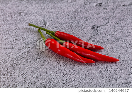Three red chili peppers on textured gray stone surface Three red chili peppers on textured gray stone surface 140244627