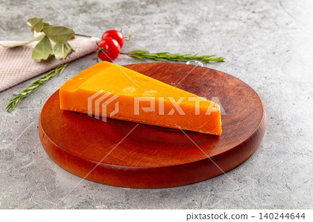 Orange cheese wedge on wooden board with rosemary and tomatoes Orange cheese wedge on wooden board with rosemary and tomatoes 140244644