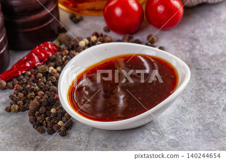 Spicy red sauce in white bowl with peppercorns and chili pepper Spicy red sauce in white bowl with peppercorns and chili pepper 140244654