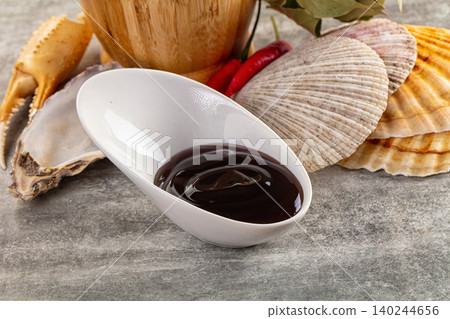 Dark seafood sauce in white bowl with shells and crab claw Dark seafood sauce in white bowl with shells and crab claw 140244656
