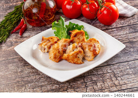 Grilled chicken pieces on white plate with fresh tomatoes and herbs on rustic wooden table Grilled chicken pieces on white plate with fresh tomatoes and herbs on rustic wooden table 140244661