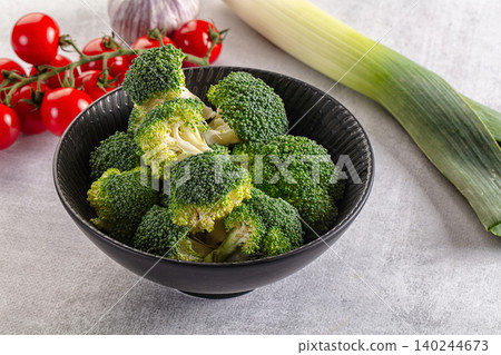 Fresh broccoli florets in bowl with cherry tomatoes, garlic, leek on grey background Fresh broccoli florets in bowl with cherry tomatoes, garlic, leek on grey background 140244673