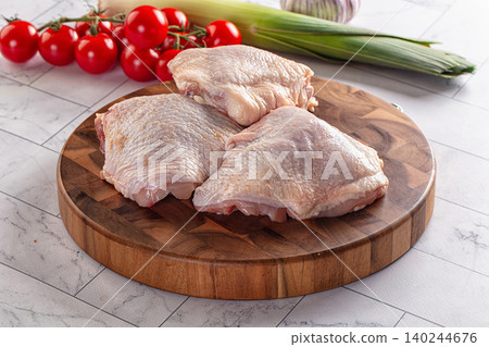 Raw chicken thighs on wooden cutting board with fresh vegetables 140244676