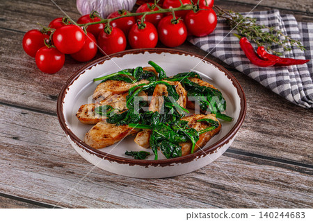 Fried chicken fillet with spinach in a ceramic bowl on a wooden table 140244683